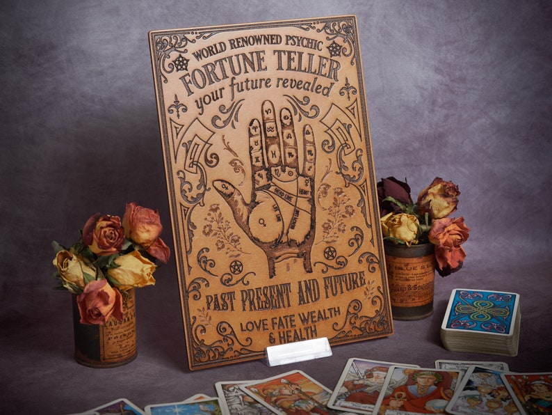 May include: A vintage-style fortune teller board with a hand drawn on it. The board is made of wood and has a brown leather-like finish. The text on the board reads "World Renowned Psychic Fortune Teller Your Future Revealed Past Present and Future Love Fate Wealth & Health".