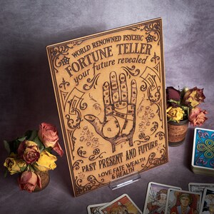 May include: A wooden sign with a vintage aesthetic, featuring a hand with lines and symbols, and the text "WORLD RENOWNED PSYCHIC FORTUNE TELLER your future revealed PAST PRESENT AND FUTURE LOVE FATE WEALTH & HEALTH".