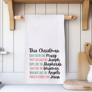 May include: White waffle-weave kitchen towel with the text "This Christmas: Have Faith Like Mary, Trust in God Like Joseph, Hope Like the Shepherds, Seek Like the Wisemen, Worship Like the Angels, Forgive Others Like Jesus."