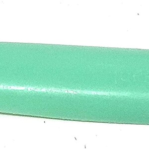 May include: A light green plastic comb with a serrated edge on one end. The comb is long and slender, with a smooth, curved handle. The serrated edge has small, evenly spaced teeth.