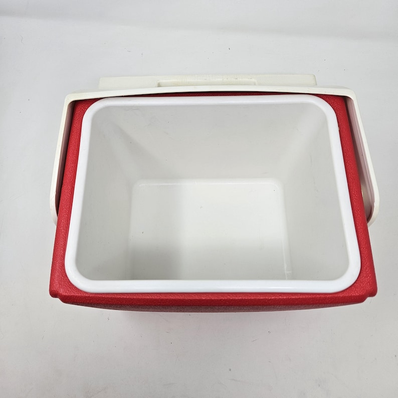 Puede incluir: Nevera roja y blanca con tapa blanca e interior rojo. La nevera est&aacute; vac&iacute;a.