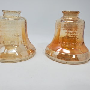 May include: Two vintage glass Liberty Bell jars in a caramel color with iridescent finish. The jars are embossed with the words "Liberty Bell" and "Made in USA".