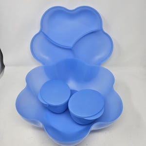 May include: A blue plastic serving dish with a divided lid and two smaller blue bowls. The dish is shaped like a flower with five petals.