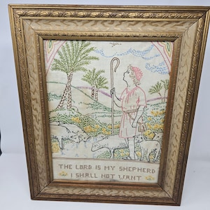 May include: A framed embroidery depicting a shepherd with a staff and sheep in a field. The embroidery is on white fabric with colorful thread. The text "The Lord is my Shepherd I shall not want" is at the bottom of the embroidery.