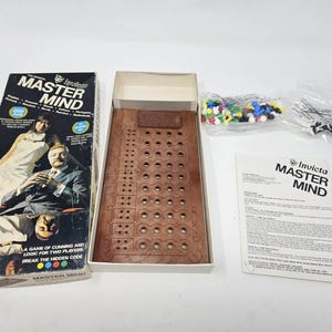 May include: A vintage Master Mind board game set. The box features the game's name and images of people. The set includes a wooden game board, colored pegs, and instructions. The game is designed for two players.