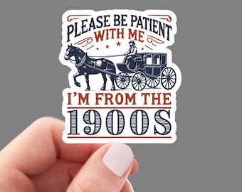 Op de afbeelding: Een witte sticker met een blauw en rood ontwerp. De sticker toont een door een paard getrokken koets en de tekst "Wees geduldig met me, ik kom uit de jaren 1900".