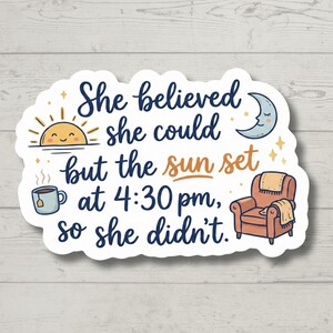 May include: A white sticker with the text "She believed she could but the sun set at 4:30 pm, so she didn't." The sticker features illustrations of a sun, a teacup, a crescent moon, and a cozy armchair.