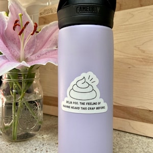May include: A lavender water bottle with a black lid and handle. A white sticker with a black outline of a pile of poop and the text "Deja poo. The feeling of having heard this crap before." is on the bottle.