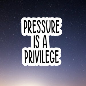 May include: A white sticker with black text against a dark blue background with white stars. The text reads "Pressure is a Privilege."