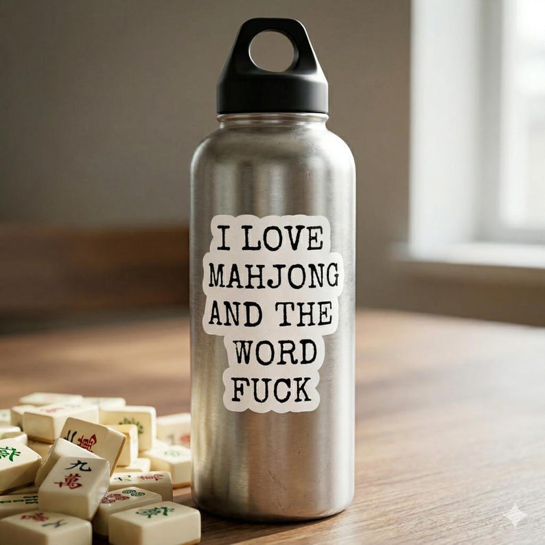 May include: A stainless steel water bottle with a black cap and the text "I LOVE MAHJONG AND THE WORD FUCK" in a white sticker. Mahjong tiles are in the foreground.
