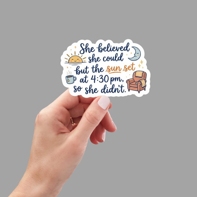 May include: A white sticker with the text "She believed she could but the sun set at 4:30 pm, so she didn't." The sticker features illustrations of a sun, moon, teacup, and armchair.