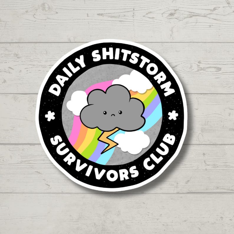May include: A black and white sticker with the text "Daily Shitstorm Survivors Club" in a circle around a cartoon cloud with a rainbow and lightning bolt.