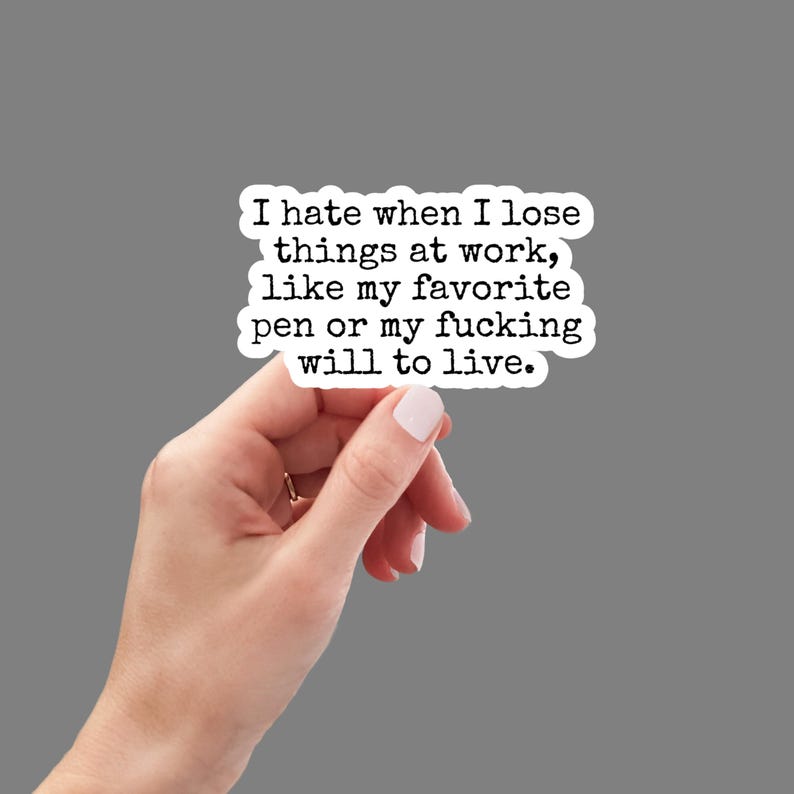 May include: A white sticker with black text held by a hand. The text reads: "I hate when I lose things at work, like my favorite pen or my fucking will to live."
