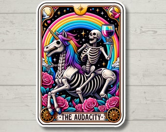 May include: A tarot card illustration featuring a skeleton riding a rainbow unicorn, holding a glass of wine. The card is set against a black background with stars and a rainbow. The text "THE AUDACITY" is printed at the bottom of the card.