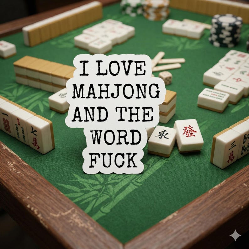 May include: A green Mahjong game board with wooden trim, scattered tiles, and stacks of chips. A sticker with the text "I LOVE MAHJONG AND THE WORD FUCK" is in the center of the image. The tiles are beige with black and red markings.