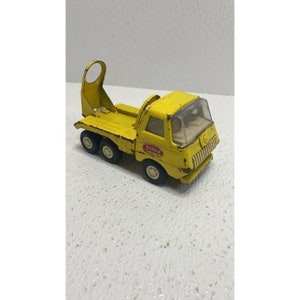 May include: Yellow Tonka toy truck with a flatbed and a raised metal bar. The truck has a clear plastic windshield and a red Tonka logo on the side.