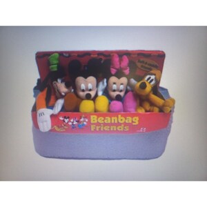 May include: A collection of Disney Beanbag Friends plush toys, including Mickey Mouse, Minnie Mouse, Goofy, and Pluto, displayed in a red and gray container. The container has the words "Beanbag Friends" printed on it.