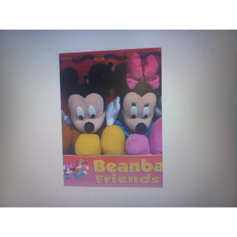 May include: A boxed set of plush toys featuring Mickey and Minnie Mouse. Mickey has black ears and a yellow body, while Minnie has a pink bow and a pink and purple body. The box reads "Beanba Friends".