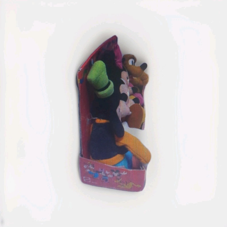 May include: A boxed set of Disney plush toys featuring Goofy, Mickey Mouse, and Pluto. Goofy is wearing a green hat and black outfit. The box is pink with Disney character graphics.