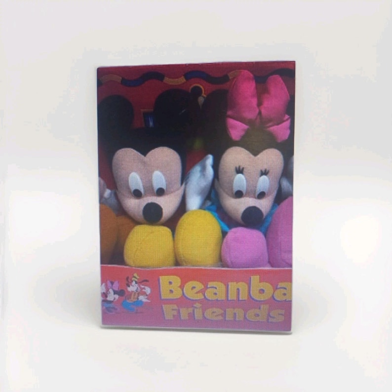 May include: A boxed set of plush toys featuring Mickey and Minnie Mouse. Mickey has black ears, a tan face, and yellow shorts. Minnie has a pink bow and dress, with a tan face. The box reads "Beanbag Friends" with Disney characters.