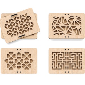 May include: Four wooden boxes with intricate laser-cut designs. The designs include a geometric pattern, a sunburst pattern, a heart pattern, and a maze pattern.