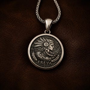 A silver pendant necklace featuring a detailed circular charm. The charm depicts a woman with long hair, flanked by two stylized animal figures. The pendant hangs from a delicate silver chain, creating an elegant accessory.