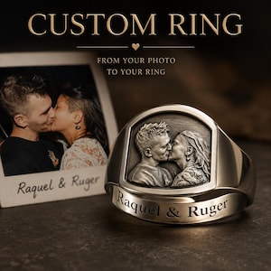 May include: A metallic ring featuring a raised, detailed relief of a couple kissing on its face. The band is engraved with the text 'Raquel & Ruger'. Beside the ring is a photograph of the same couple with the text 'Raquel & Ruger' below it.
