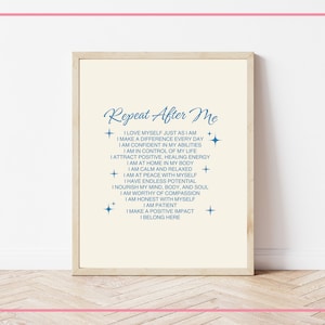 May include: A printable wall art poster with a cream background and blue text. The text reads "Repeat After Me" and includes a list of positive affirmations. The poster is framed in a light wood frame.