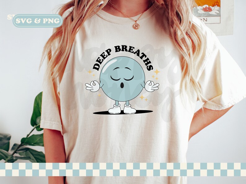 May include: A white t-shirt with a blue cartoon character meditating with the text "Deep Breaths" in black.