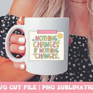 Puede incluir: Taza de cer&aacute;mica blanca con un dise&ntilde;o rosa, amarillo, azul y verde. La taza presenta el texto "Nada cambia si nada cambia" con una carita sonriente y estrellas.
