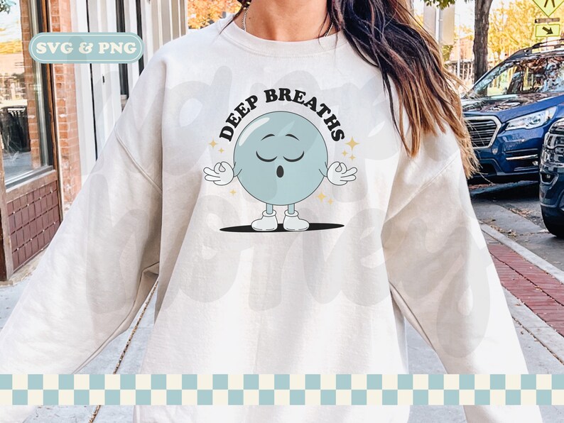 May include: A white sweatshirt with the text "DEEP BREATHS" in black letters. A cartoon blue circle with a face and arms is in the center of the text. The circle has its eyes closed and is holding its hands in a yoga pose.