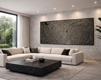 May include: A modern living room featuring a large sectional sofa in a neutral color, accented with dark pillows. A black marble coffee table sits in front of the sofa, and a large abstract artwork hangs on the wall. A potted plant adds a touch of greenery.