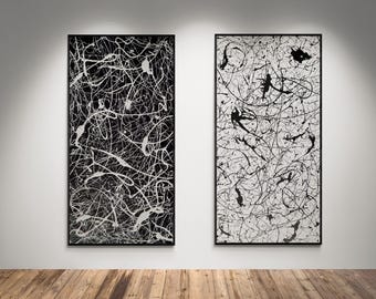 May include: Two rectangular wall art pieces in black frames. The left piece features white paint splatters and lines on a black background. The right piece features black paint splatters and lines on a white background, creating a high-contrast set.