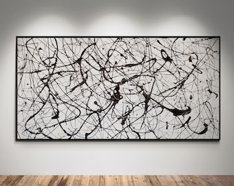 May include: Abstract expressionist painting with black paint splatters on a white background, framed in black. The artwork is displayed on a white wall above a wooden floor, illuminated by spotlights.