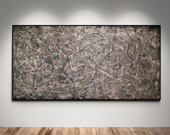 May include: Abstract expressionist painting with a black frame. The artwork features a textured, neutral-toned background with overlapping lines in white, blue, and black, creating a dynamic composition. The painting is displayed on a white wall.