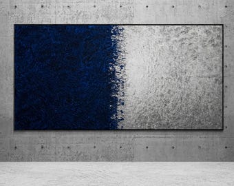 May include: Abstract wall art featuring a textured design. The artwork is divided into two halves: one in deep navy blue and the other in a textured silver-gray. The piece is framed in black and mounted on a concrete wall.