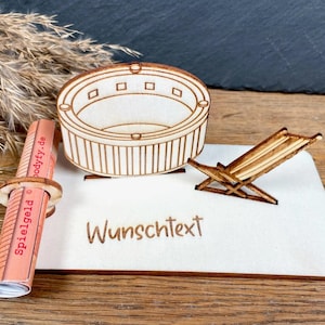 Könnte beinhalten: Ein heller Holzsockel mit einem lasergeschnittenen Whirlpool und einem kleinen Liegestuhl. Der Sockel enthält eine kreisförmige Halterung mit einem zusammengerollten Zettel mit der Aufschrift Spielgeld und dem Text Wunschtext.