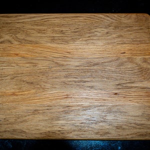 May include: A rectangular wooden cutting board with a natural wood grain finish.