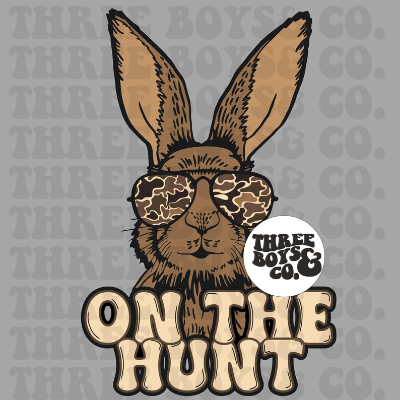 May include: A brown rabbit wearing camouflage sunglasses with the text "ON THE HUNT" in brown and white letters. The rabbit is wearing a round sticker that says "THREE BOYS & CO."