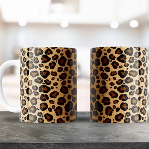 Könnte beinhalten: Zwei weiße Keramikbecher mit einem braunen und schwarzen Leopardenmuster.