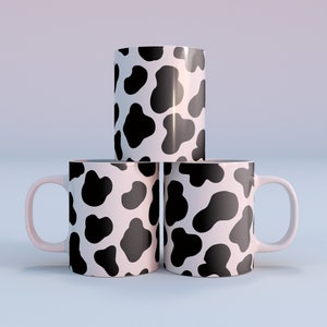 May include: Three white ceramic mugs with a black cow print design. The mugs are stacked on top of each other.