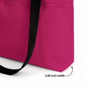 May include: A bright pink tote bag featuring black fabric handles. The bottom panel of the bag is clearly labeled with text indicating a 3.46 inch width. The bag is constructed from a solid-colored textile material with visible stitching along the seams.