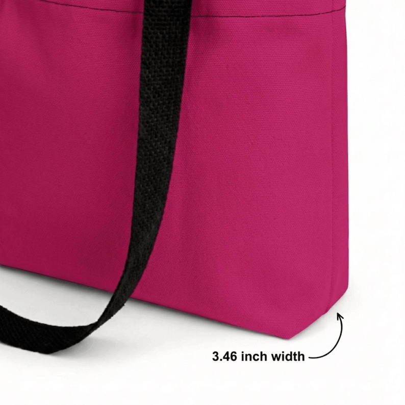 May include: A bright pink tote bag featuring black fabric handles. The bottom panel of the bag is clearly labeled with text indicating a 3.46 inch width. The bag is constructed from a solid-colored textile material with visible stitching along the seams.