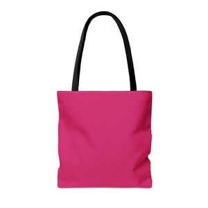 May include: A solid hot pink tote bag featuring two long, sturdy black fabric handles attached to the top. The bag has a rectangular body with a flat base and a clean, minimalist design, providing a vibrant pop of color for daily carrying needs.