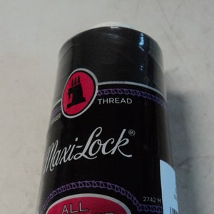 Peut inclure: Une bobine de fil noir Maxi-Lock Tout Usage en polyester. La bobine est étiquetée avec le nom de la marque et la longueur du fil, 2742 mètres.