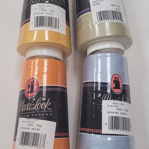 May include: Four spools of Maxi-Lock Serger Thread in different colors: gold, papaya, khaki, and blue mist. Each spool contains 3000 yards of thread and has a barcode label with the color name, yardage, and product number.