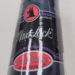 May include: A spool of Max Lock All Purpose Serger Thread in a dark blue color. The spool is labeled with the brand name, thread type, and length of 2742 meters.