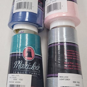 May include: Four spools of Maxi-Lock serger thread in blue, pink, teal green, and light grey. Each spool has a label with the color name, thread type, yardage, and barcode. The spools are stacked on top of each other.