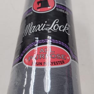 May include: A spool of Maxi-Lock All Purpose Spun Polyester thread in a dark gray color. The spool has a red and black label with the Maxi-Lock logo and the text "All Purpose Spun Polyester".