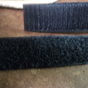 May include: Two strips of black hook and loop fastener tape. The tape is made of a soft, fuzzy material.